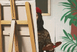 gif de um pintor, ele estu00e1 coberto por parte da sua tela de pintura quando de repente ele se movimenta para o lado e mostra seu pincel