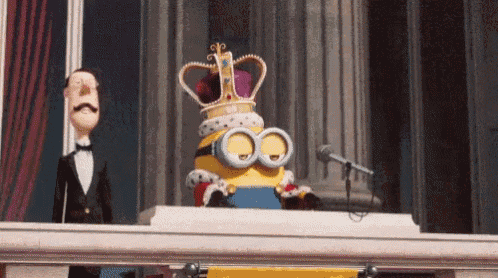 gif de uma cena do filme Minions, em que um minion usa uma coroa e um manto real e, de cima de um castelo, faz um discurso para uma plateia de minions que o aplaude